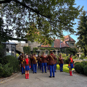 Traditionelle Blasmusikkapelle marschiert in Uniformen in den Innenhof eines alten Schlosses ein.