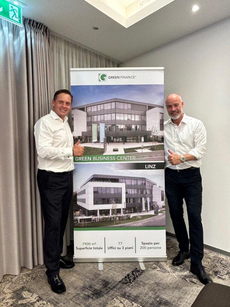Zwei Männer in Businesskleidung präsentieren stolz ein Roll-Up mit dem Green Business Center Linz.