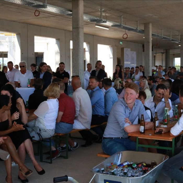 Menschen an Tischen bei der Gleichenfeier für das Green Business Center Linz der Green Finance