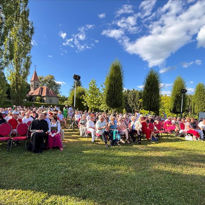 Zahlreiche Besucherinnen und Besucher sitzen im Freien vor einer historischen Schlosskapelle beim Schlössersingen-Event.